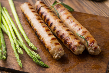 Fried  sausage with asparagus. on  wooden cutting board.