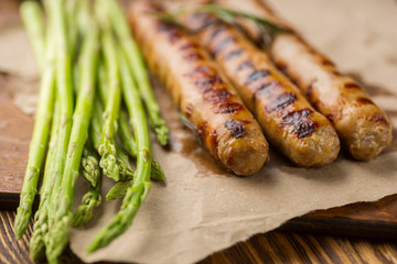 Grilled sausage with asparagus on craft paper.