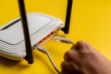 hand conncecting the ethernet wire cable with wi-fi remote point