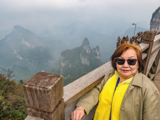 Beautiful senior asia woman on wooden bridge crossing the mountain on tianmen mountain national park at Zhangjiajie city china.landmark of hunan