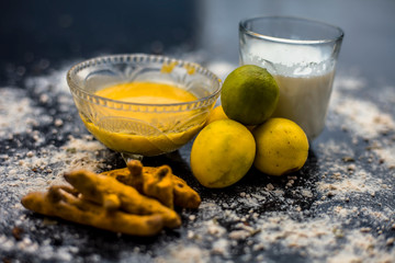 Lemon face mask on the wooden surface consisting lemon juice, gram flour or chickpea flour, turmeric or Haldi and milk in a glass bowl.For the treatment of tans.