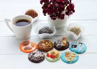Chocolate candies, a cup of coffee and a bunch of flowers for Valentine's Day on on wooden background.