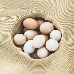 Fresh eggs in a straw hat outdoors. Concept fresh eggs with copy space for background or wallpaper