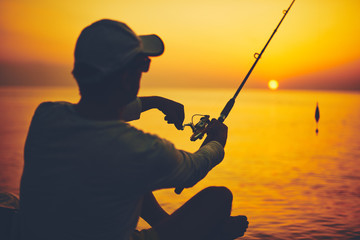Silhouette of a fisherman fishing in sunset time on the open sea.