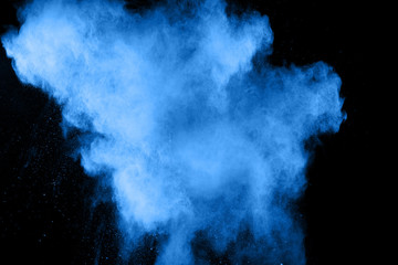 Freeze motion of blue dust explosion on black background. Throwing blue powder out of hand against...