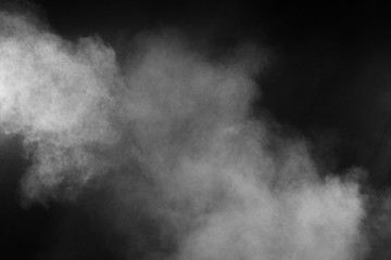 Freeze motion explosion of white powder on a black background.Stopping the movement of white dust on dark background.