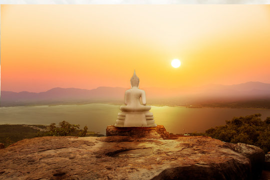 Buddha statue on mountain with sunset or sunrise background