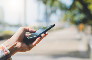 close up handsome man using hand typing mobile phones and touch screen working search with app devices outdoor in city with sunrise and building background.