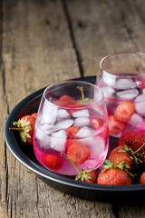 Summer Fresh Flavored Infused Water Strawberry Detox Water Healthy Diet Drink Ice cube Fresh Strawberry on Black Plate Wooden Background Cold Beverage in Glasses