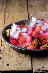 Summer Fresh Flavored Infused Water Strawberry Detox Water Healthy Diet Drink Ice cube Fresh Strawberry on Black Plate Wooden Background Cold Beverage in Glasses