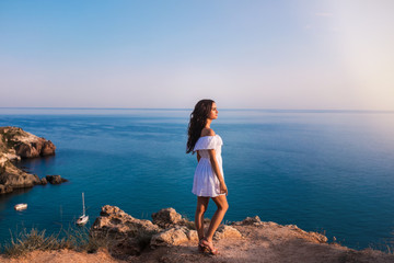 Fototapeta na wymiar Young beautiful woman on the rock in the sea.