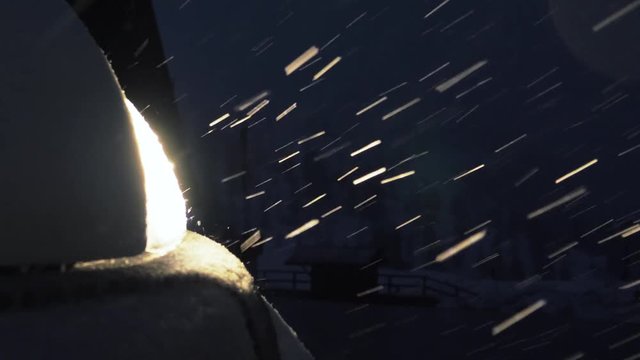 Close up shot of a car at night in the snow. Big snowflakes are falling, lousy weather.