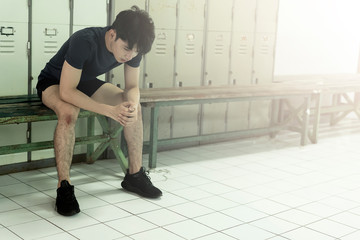 young Asian man sitting taking break upset or tired. ,sweating after a workout session at gym or University sport competition. athlete suffering breakdown to overcome. Stress and fatigue in sport.