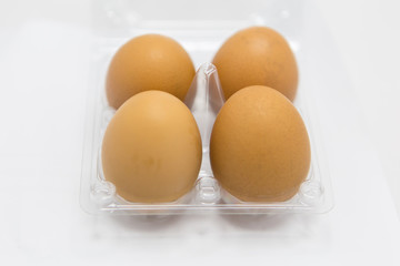 Close-up view of raw chicken eggs in egg box on white  background