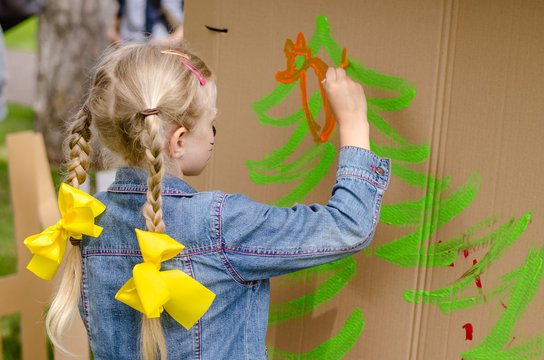 Child With Long Blond Hair In Tail And Yellow Ribbon Painting With Colors