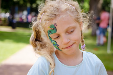 smiling girl with face painting of peacock