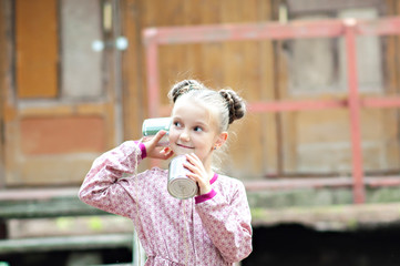 Fototapeta premium Children are testing the ancient cellular. Radio last years. Girls communicate at a distance using cans. Old technology. Children's games. Happy girls girls grandmother in the village.