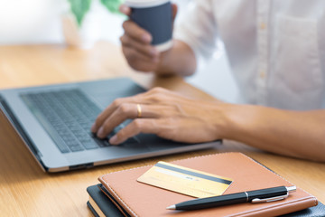 Man paying with credit card and entering security code for online shoping making a payment or purchasing goods on the internet with laptop computer, online shopping concept