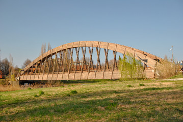 Fototapeta na wymiar a wooden bridge over a river in a park in Italy
