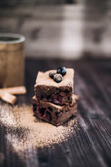 brownie cake on a dark background decorated with fresh berries and cocoa