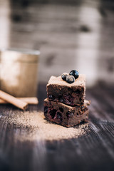 brownie cake on a dark background decorated with fresh berries and cocoa