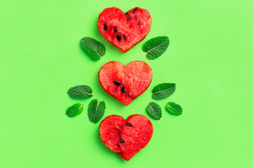 Creative summer food concept. Juicy slices of ripe red watermelon in the shape of a heart and mint...