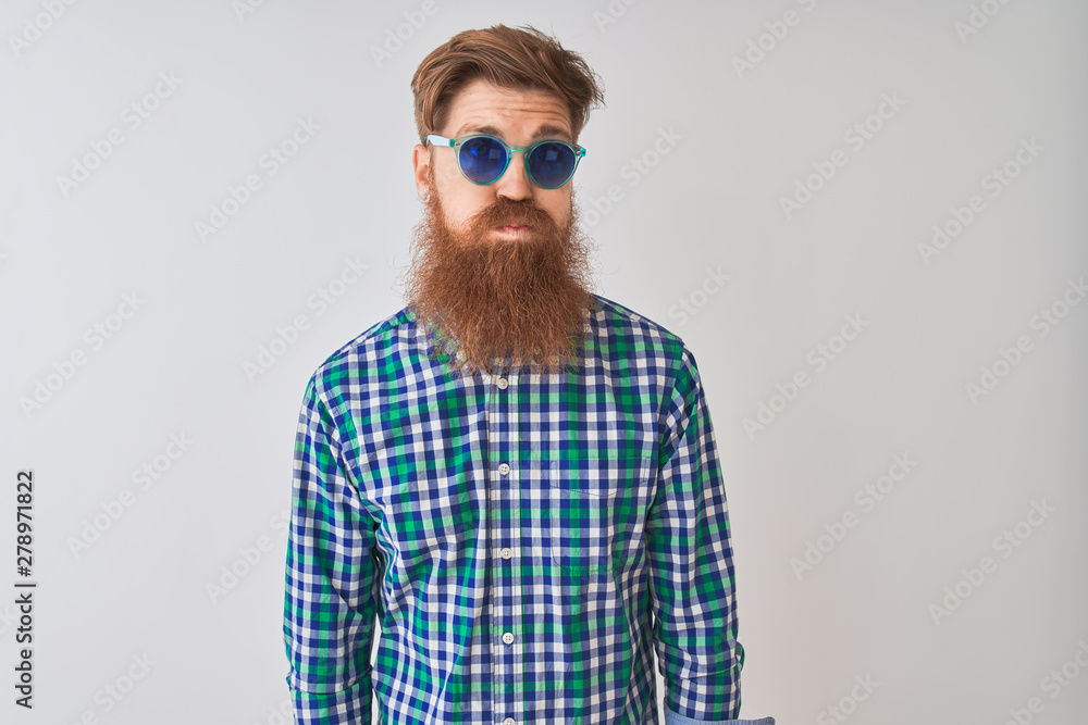 Sticker young redhead irish man wearing casual shirt and sunglasses over isolated white background puffing c