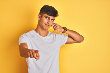 Young indian man wearing white t-shirt standing over isolated yellow background smiling doing...