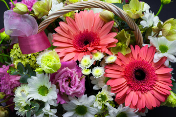 bright flower arrangement in a white basket on a dark background flowers in a wicker basket