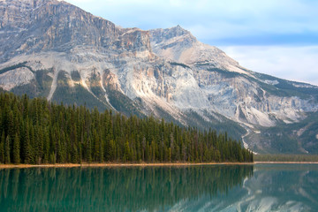A beautiful lake with high pine tree and big moutain in Banff Alberta Canada. Reflection of tree and mountain on lake.