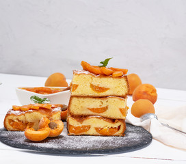 baked pieces of biscuit pie with apricots on a black graphite plate