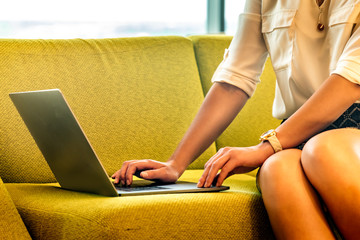 Close-up of a young woman using a laptop at home on a couch