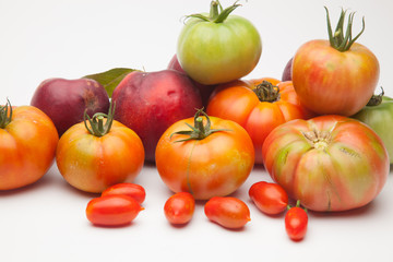 Nectarinas, tomates maduros y tomates cherri sobre un fondo blanco. Los productos han sido traidos de un huerto ecológico, cultivados sin productos químicos ni pesticidas.
