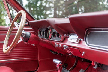 Old red cabriolet. Interior view with instruments and wooden steering wheel