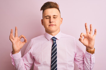 Young handsome businessman wearing shirt and tie standing over isolated pink background relaxed and smiling with eyes closed doing meditation gesture with fingers. Yoga concept.