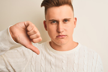 Young handsome man wearing casual t-shirt standing over isolated white background with angry face,...
