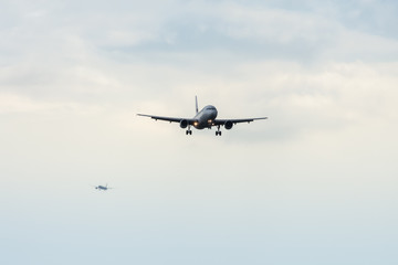 Rush hour at the airport: A silhouette of a landing airplane with second one lining up at a distance.