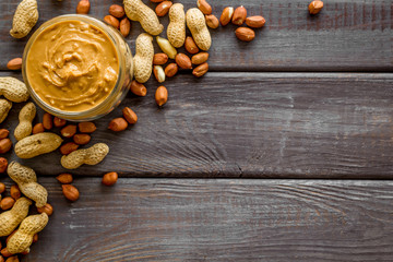 Make peanut butter with paste in glass bowl on wooden background top view copyspace