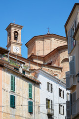 Fototapeta na wymiar Misericordia church back part in red bricks and old buildings with balcony in a sunny summer day, blue sky in Mondovi, Italy