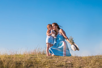 Young mother and daughter, hugging and playing in a golden field of sunshine.