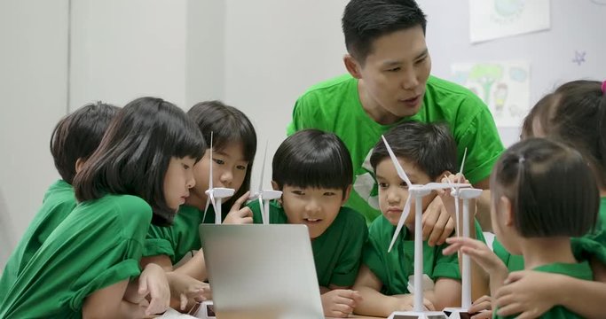 Informative ecology teacher use laptop computer having lesson about recycling to elementary students in class at the elementary school.