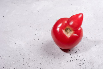 Close-up one ugly ripe red tomato on grey concrete background. 