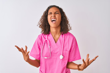 Young brazilian nurse woman wearing stethoscope standing over isolated white background crazy and...
