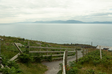 wood fenced path with the sea in the background