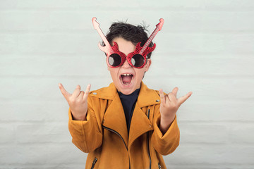 child with sunglasses doing rock symbol with hands up