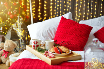 breakfast in bed, tray with cup of coffee and croissant. Modern bedroom interior. Romantic morning surprise.