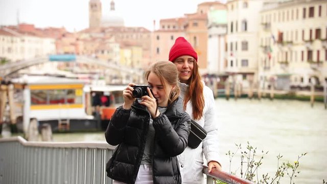 Two young women on the streets of Venice. One of them take a photo of the surroundings
