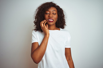 Fototapeta na wymiar Young african american woman wearing t-shirt standing over isolated white background touching mouth with hand with painful expression because of toothache or dental illness on teeth. Dentist concept.