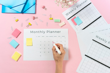 Woman writing at planner on pink pastel background