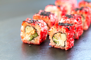 Fresh traditional Japanese sushi rolls on black slate. Selective focus. Portion Sushi close-up.